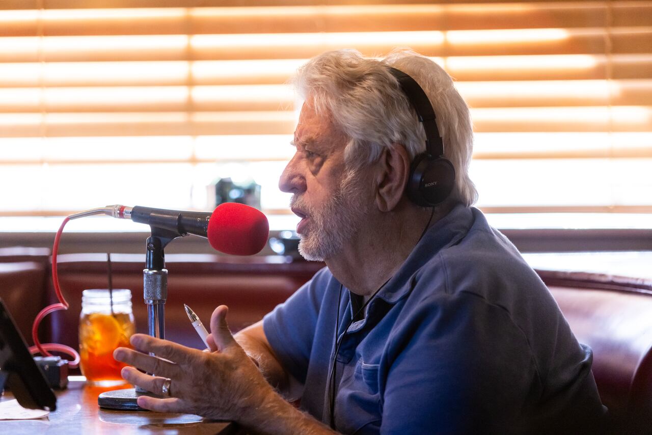 Al Wynn wearing headphones and speaking into a red microphone during Coffee Break.